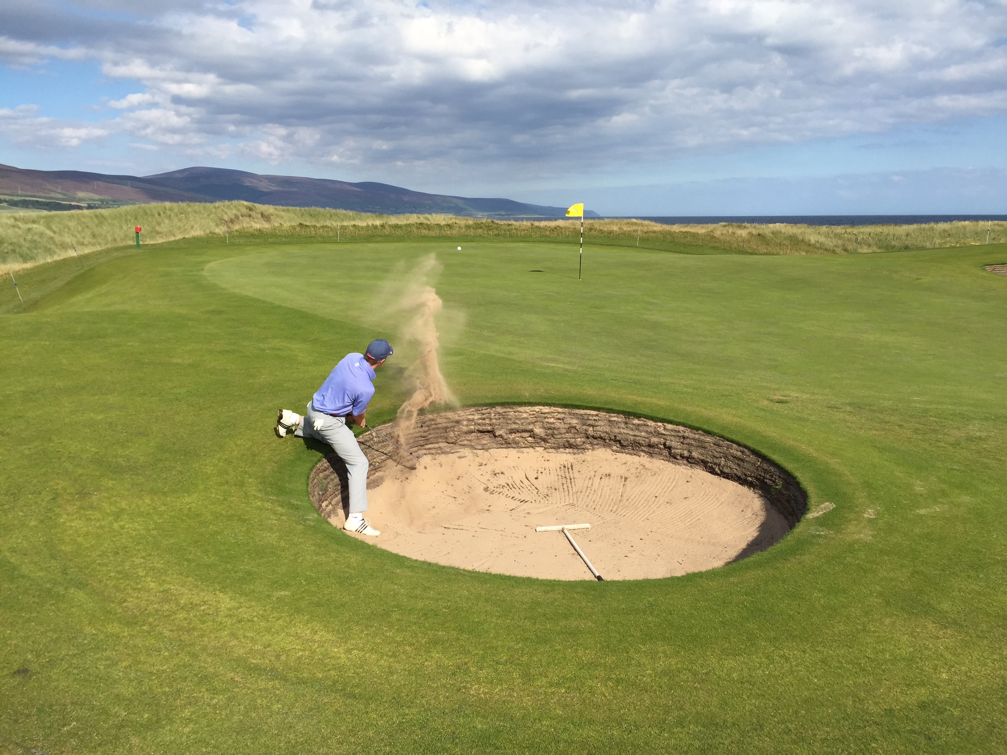 Marty hitting a golf ball out of a bunker in Brora, Scotland